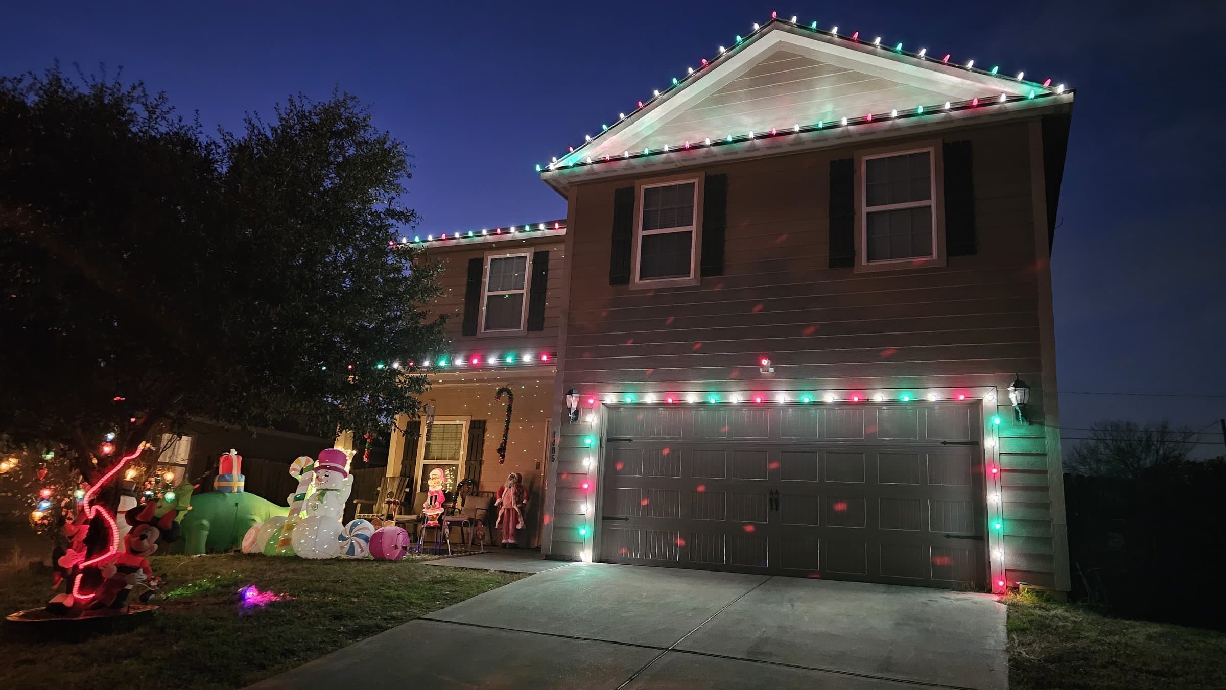 Two-story home lit up with a colorful rooftop Christmas light display